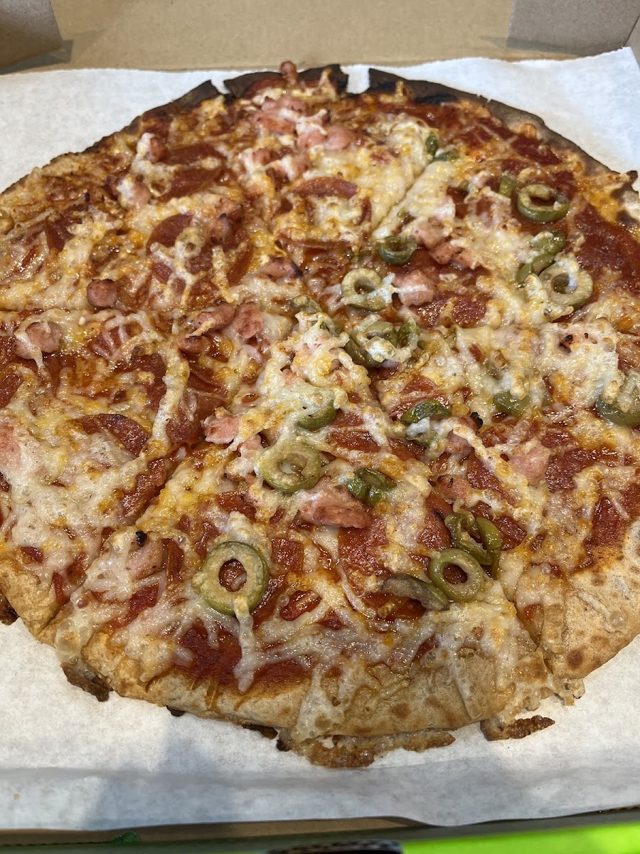 Cauliflower crust pizza with peperoni, bacon and green olives on half with vegan cheese. So good!