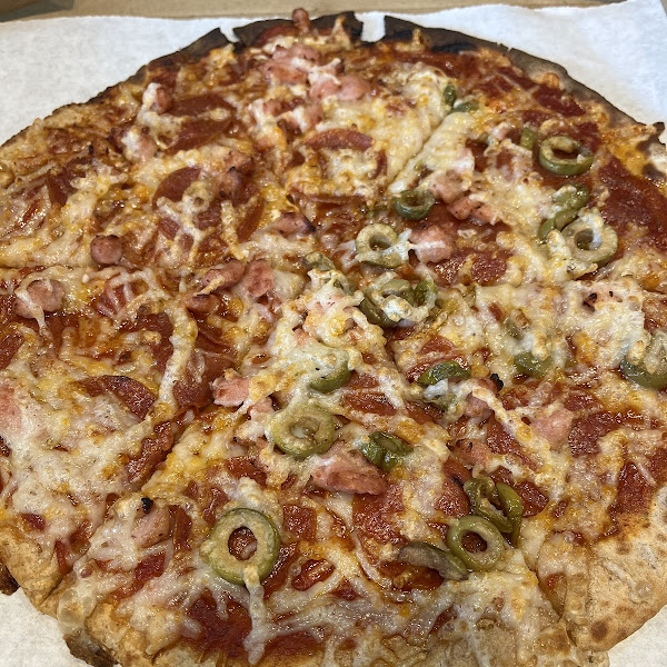 Cauliflower crust pizza with peperoni, bacon and green olives on half with vegan cheese. So good!