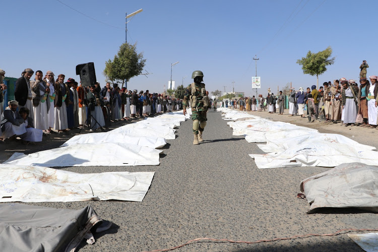 A Houthi policeman walks past bodies of victims of air strikes on detention center in Yemen's northern province of Saada, Yemen January 25, 2022.