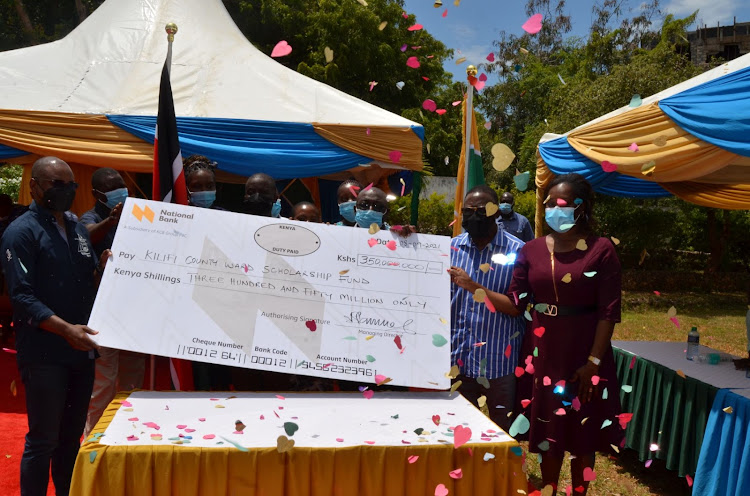 Kilifi Governor Amason Kingi with Education executive Rachael Musyoki shows the dummy cheque during hand over ceremony to the beneficiaries of the scholarship.