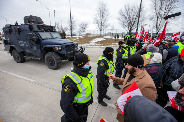 Police and protesters confront each other after a court ordered that truckers and supporters were prevented from blocking access to the Ambassador Bridge, which connects Detroit and Windsor, in Windsor, Ontario, Canada, February 12 2022. Picture: CARLOS OSORIO/REUTERS