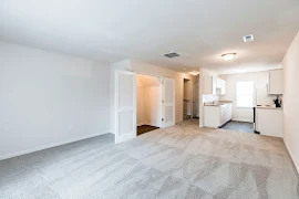 Living room with light carpet, light walls and trim, coat closet, and view of kitchen