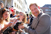 Prince Harry is greeted by well-wishers and a pet dog at the Invictus Games One Year To Go event.