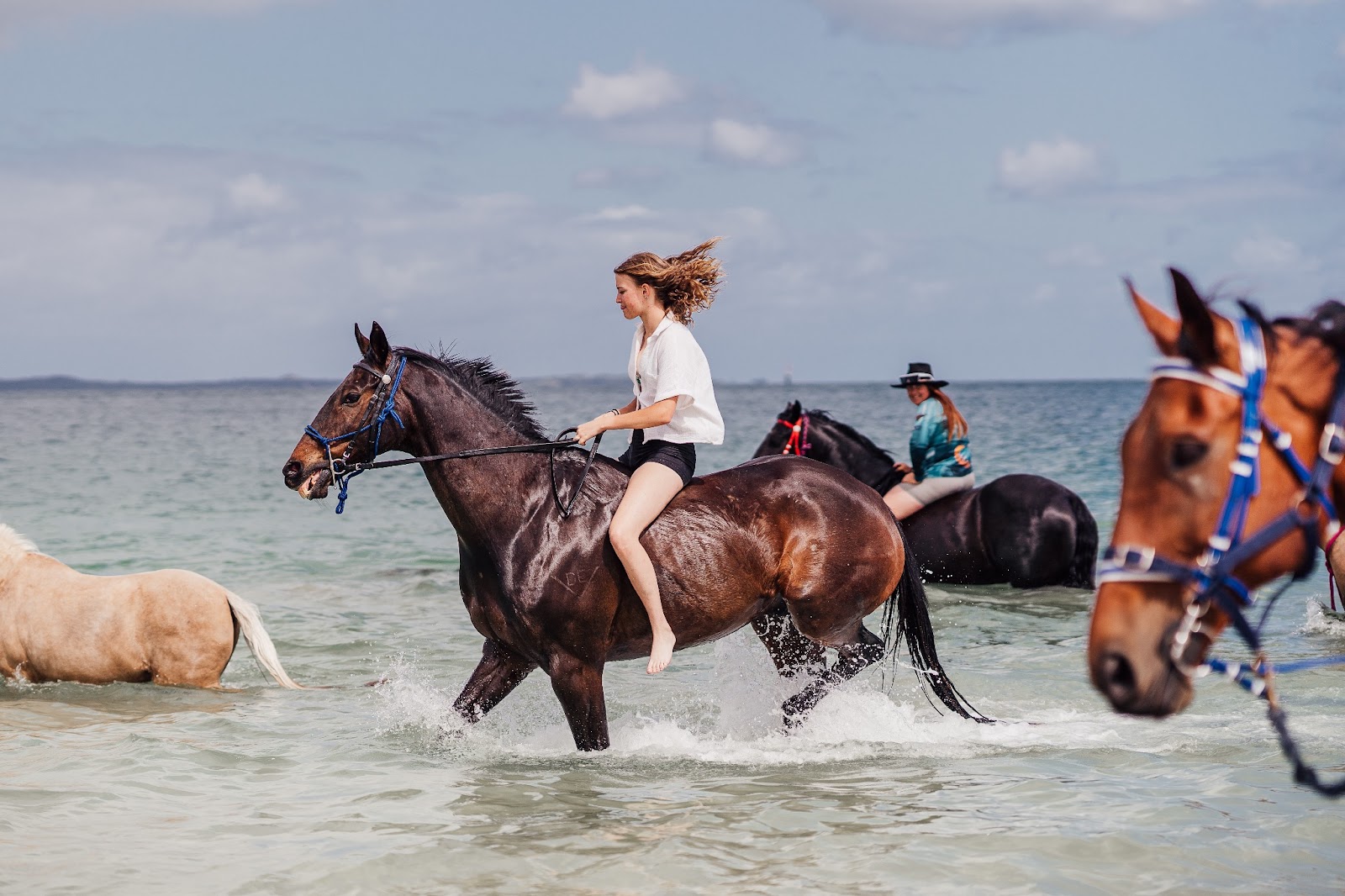An enchanting image of a people riding through the water with thoroughbred horses at a Jamaican resort. Experience the magic of sharing the water with these majestic creatures.