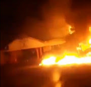 A screenshot from a video showing the Izingolweni community hall, a municipal building and a grader engulfed in flames after protesters set them alight on Tuesday night.