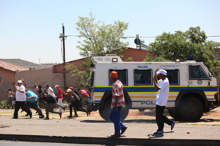 Protesters flee as police start firing rubber bullets during a protest in Westbury, Johannesburg, on October 1 2018.