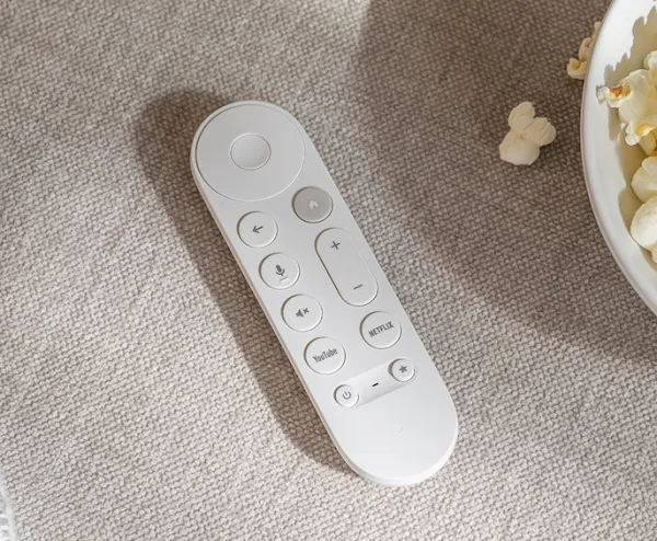 The remote control for Google TV Streamer next to a bowl of popcorn