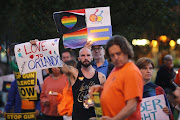 People hold up signs for passing cars at a candlelight vigil in West Hollywood, California, following the early morning shooting at a gay nightclub in Orlando, Florida, U.S. June 12, 2016. Picture Credit: Reuters