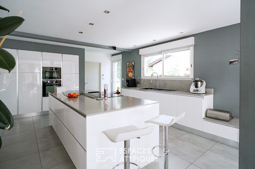 Modern white kitchen with central island in this luxury house for sale in Macon ($692,442 - 228 m²)