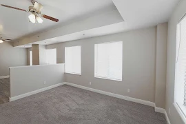 Studio floorplan with half wall separating living area and bedroom area, gray carpet and walls, white trim, and windows