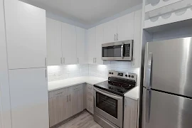 Kitchen with white upper cabinets and grey wood lower cabinets. White stone counters and white stone mosaic backsplash.