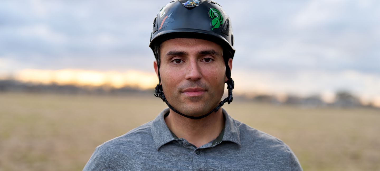 Profilaufnahme von Bourhan Yassin mit einem Helm in einem Feld, bevor er auf einen Baum klettert