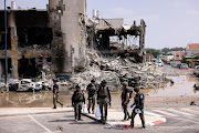 Israeli security gather near a rifle at the site of a battle following a mass infiltration by Hamas gunmen from the Gaza Strip, in Sderot, southern Israel October 8, 2023.