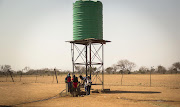 School children from Immerpan Primary School are having a water break under a Jojo water tank on a friday afternoon, during lunch time. 