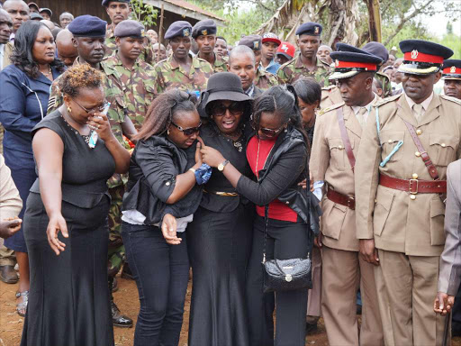 ADORED BY MANY: Mary Nyambura (centre), widow of KDF soldier Albert Thiong’o (inset), at the grave where her husband was laid to rest at their home in Karai village, Gatamaiyu location, Lari constituency, on Wednesday.