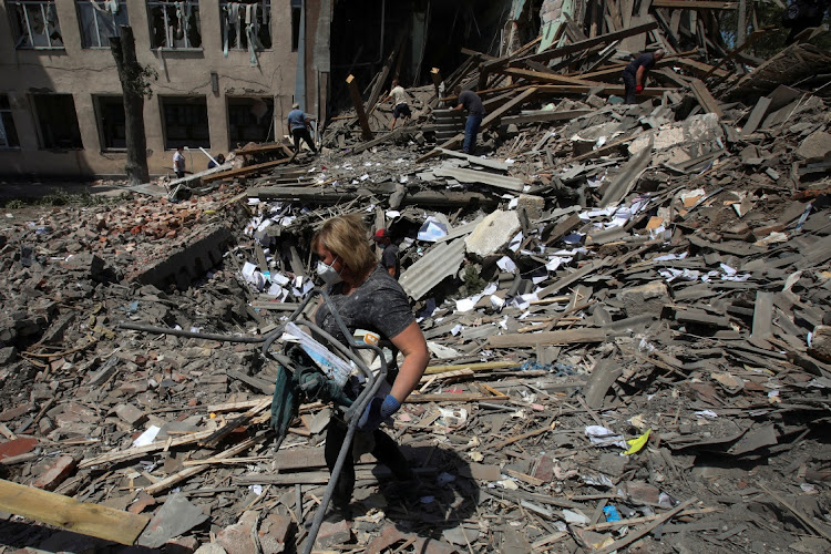 People remove debris of a building of the lyceum of railway transport destroyed by a missile strike, as Russia's attack on Ukraine continues, in the town of Liubotyn, in Kharkiv region, Ukraine June 20, 2022.