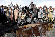 Men look at human remains following an overnight fire on the outskirts of Kabul, Afghanistan, on May 2 2021. 