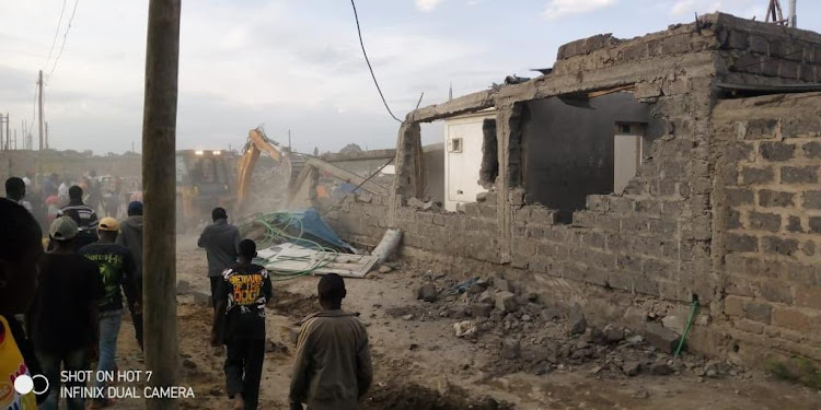 Residents of Njiru watch their houses being demolished by bulldozer on March 27, 2021