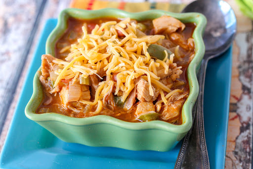 A bowl of quick pinto chicken chili with cheese on top.
