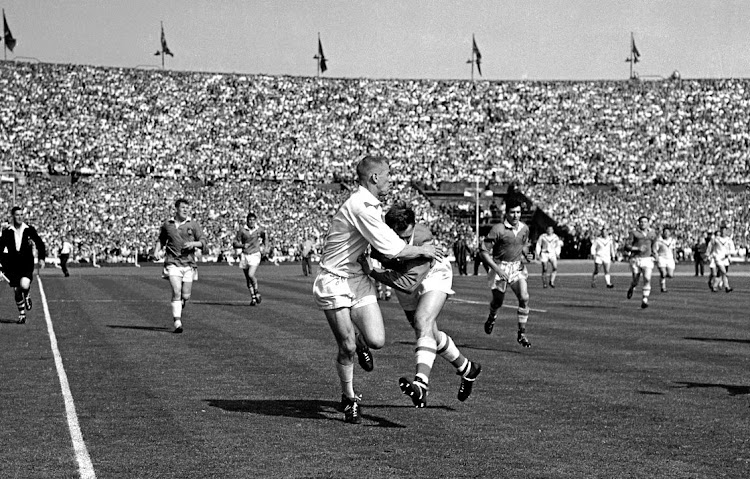 St Helen's Tom van Vollenhoven passes the ball inside as he is tackled by Wigan's F Griffiths.