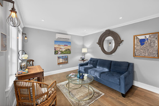 Living room with blue sofa and wall mirror in this luxury apartment / penthouse for sale in Provincetown ($949,000)