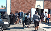 Parents and family members wait outside the Cambridge police hall in East London ahead of their meeting with the police minister and Eastern Cape premier over the deaths of 21 teenagers at Enyonbeni Tavern.