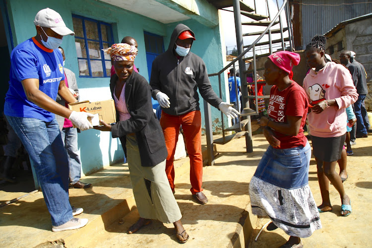 City Stars CEO Patrick Korir hands food to a Kibera Slum resident