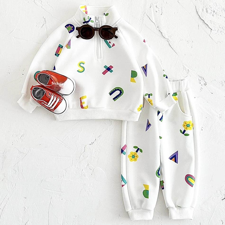 Witte letterprint baby rompertje met ritssluiting, opstaande kraag en verdikte stof. Warme en comfortabele lange mouwen overall.