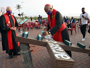 Cardinal Wilfred Napier places flowers on a cross to honour health workers, which was the theme of a beachfront Good Friday service in Durban. 