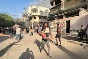 A Palestinian carries a child casualty near the site of Israeli strikes on houses in Gaza City October 28 2023.