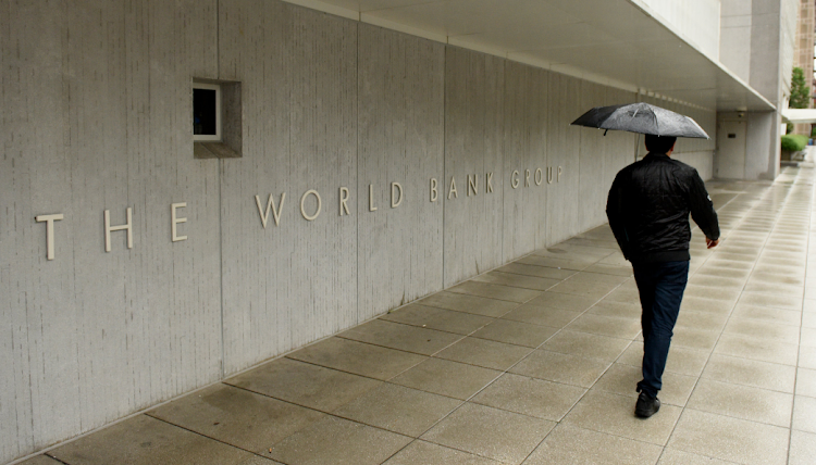 A pedestrian with an umbrella walks past the World Bank's main building in Washington DC, the US. Picture: 123RF/BUMBLEDEE