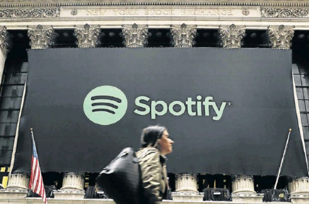 Pedestrians walk past a banner with the Spotify logo as the company lists its stock on the New York Stock Exchange with a direct listing in New York Picture: Reuters