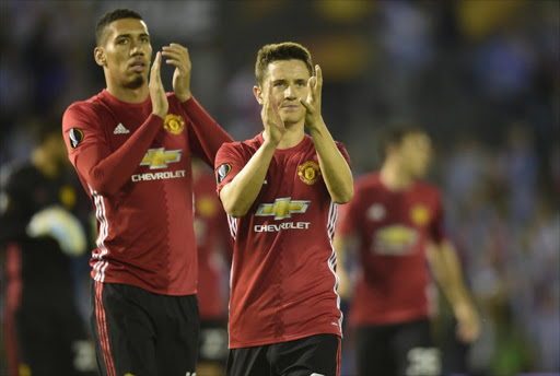 Manchester United's defender Chris Smalling (L) and Spanish midfielder Ander Herrera applaud their fans at the end of their UEFA Europa League semi final first leg football match RC Celta de Vigo vs Manchester United FC at the Balaidos stadium in Vigo on May 4, 2017. Manchester won 1-0.