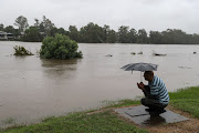 A man smokes a cigarette next to the swollen Nepean River as the state of New South Wales experiences widespread flooding and severe weather, in Sydney, Australia, March 21, 2021.  