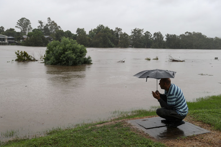 A man smokes a cigarette next to the swollen Nepean River as the state of New South Wales experiences widespread flooding and severe weather, in Sydney, Australia, March 21, 2021.