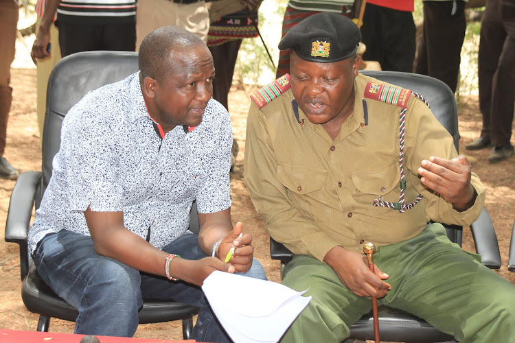 Tiaty MP William Kamket confers with Rift Valley Regional Coordinator Mwongo Chimwaga during food donation at Nginyang in his constituency on Wednesday.