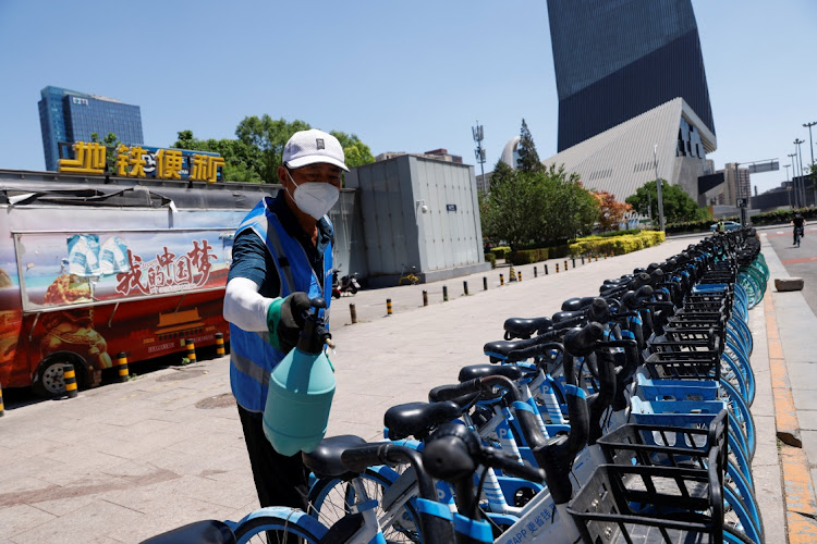 A worker wearing a face mask sprays disinfectant on shared bicycles outside a subway station in the CBD, amid the Covid-19 outbreak in Beijing, China, on May 30. Picture: REUTERS/CARLOS GARCIA RAWLINS