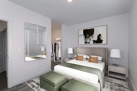 Furnished bedroom with gray carpet, light walls and trim, walk-in closet, queen-size bed with headboard, and decor