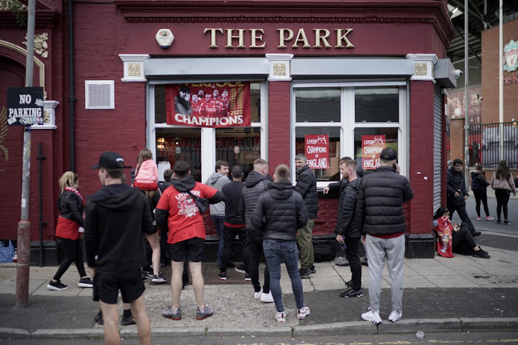 Liverpool fans watch the English Premier League against Chelsea through the window of The Park pub, next to Anfield Stadium on July 22, 2020 in Liverpool, England