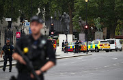 Armed police stand in the street after a car crashed outside the Houses of Parliament in Westminster, London, Britain, August 14, 2018. 