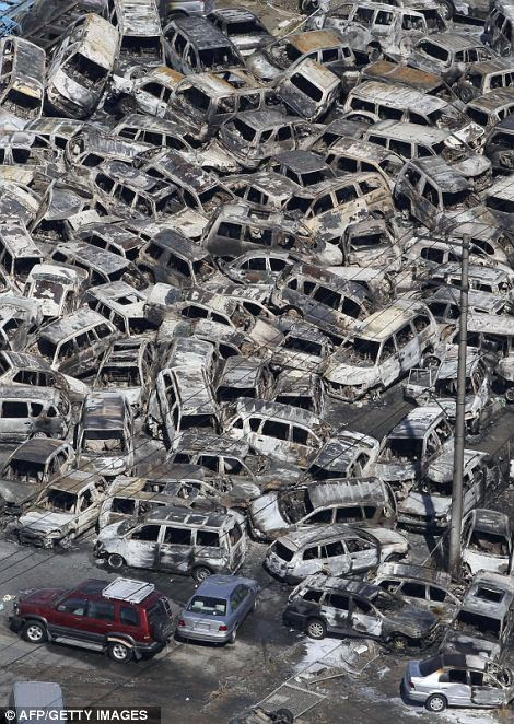 A pile of burnt out vehicles that were ready to be exported are piled in disarray at a port at Tokai village in Ibaraki prefecture