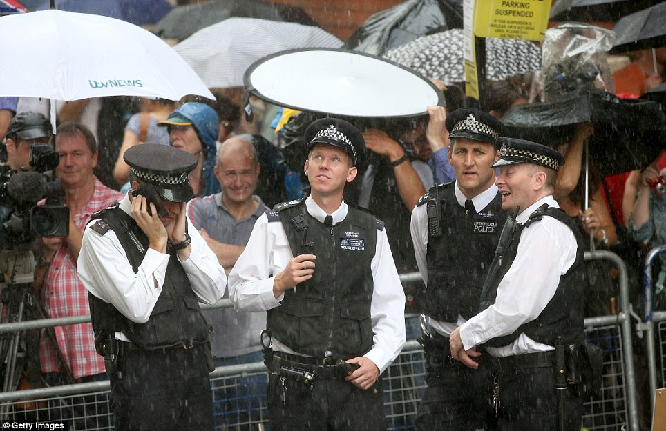 Drenched: Police officers keeping the St Mary's Hospital secure are not allowed to get out of the heavy downpours