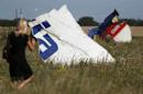 A woman walks past wreckage at the crash site of Malaysia Airlines Flight MH17 near the village of Hrabove (Grabovo)