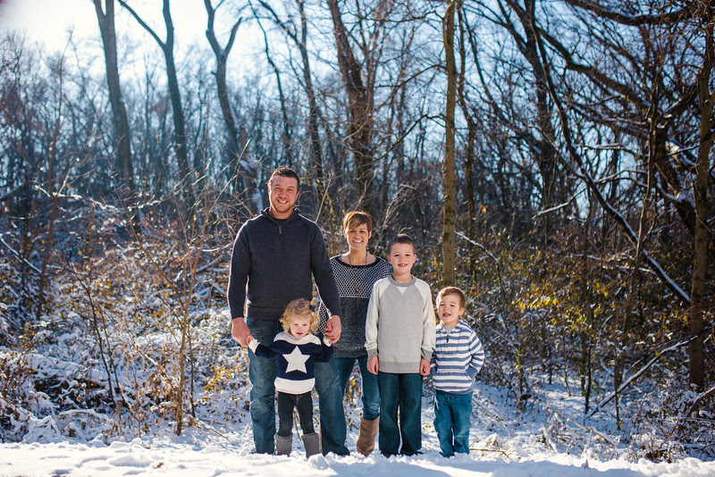 Pictures outside with a family of five with little boys and a little girl in the woods by a covered bridge with snowy backgrounds. The Harshbarger family had a fun time playing in the snow outside making for beautiful candid moments by Rockford IL Portrait Photographer, Mindy Joy Photographer.