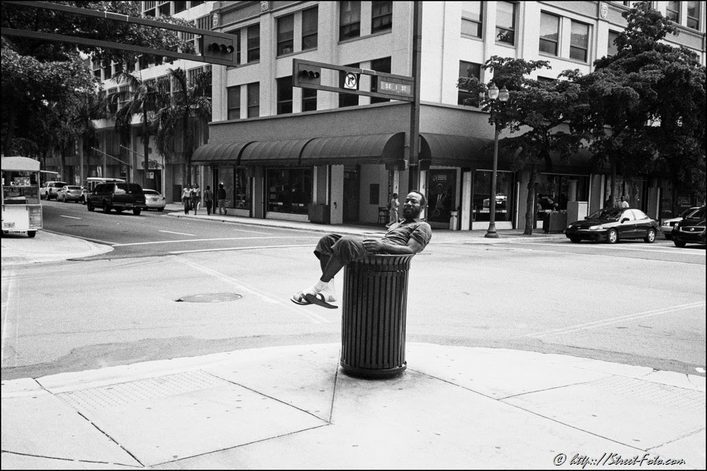 Man resting on top of the garbage can in Downtown Miami, Florida, USA, 2011. Street Photography of Miami, San Francisco and Key West by Emir Shabashvili, see http://street-foto.com, http://miamistreetphoto.com, http://miamistreetphotography.com or http://miamistreetphotographer.com