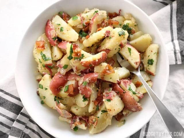 German Potato Salad is coated in a tangy bacon vinaigrette and is the perfect side for all your summer grilling. BudgetBytes.com
