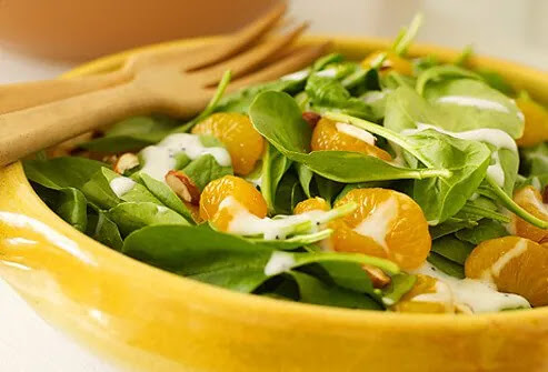 Spinach salad topped with a bit of dressing and mandarin oranges.