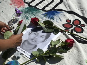 Estudante deposita flores e vela no retrato de um dos estudantes desaparecidos durante protesto na Cidade do México, na quarta-feira (8) (Foto: AFP Photo/Ronaldo Schemidt)