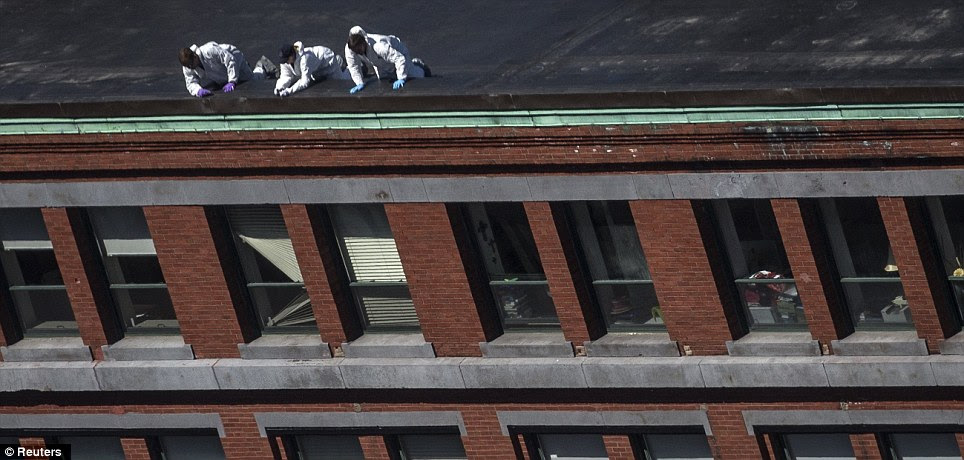 Needle in a haystack: Investigators lean over the rooftop of a building located above the site of the bomb blast 