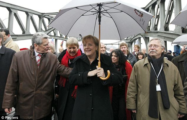 German Chancellor Angela Merkel (c) walks across the Bornholmer Strasse Bridge today, retracing her steps from East Germany 20 years ago